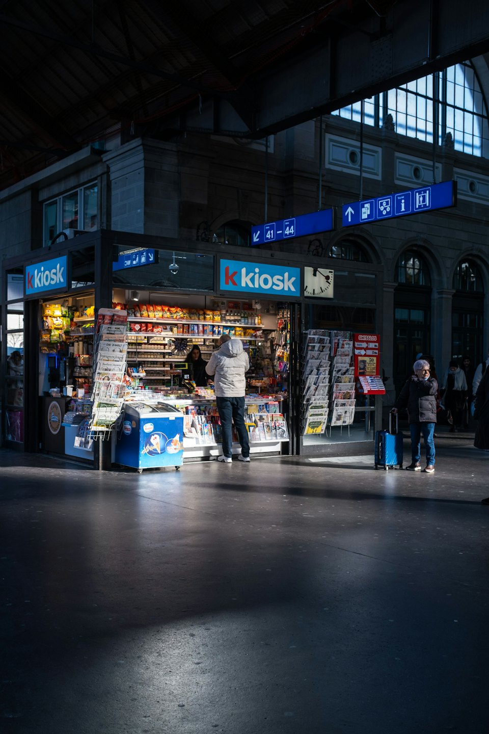 Un cliente effettua un acquisto presso una biglietteria automatica in una stazione ferroviaria al coperto.